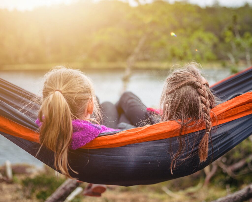 two girls sitting in a hammock working on homeschool. Their parents are learning how to homeschool